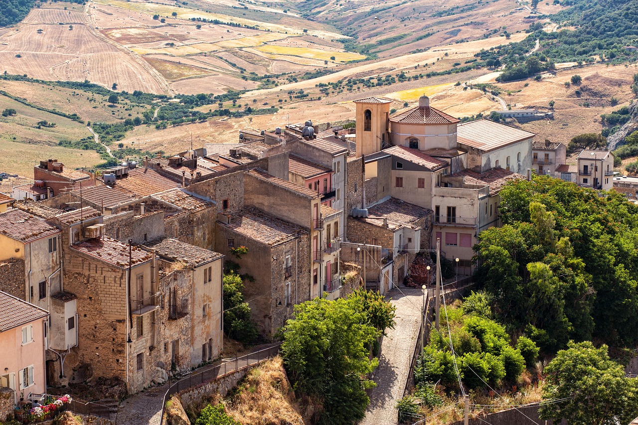 Vista panoramica del borgo siciliano con piatti tipici tradizionali in primo piano.