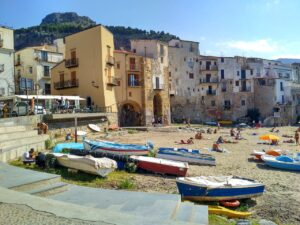 Spiaggia di San Vito Lo Capo affollata di turisti sotto il sole estivo, con mare cristallino e sabbia dorata.