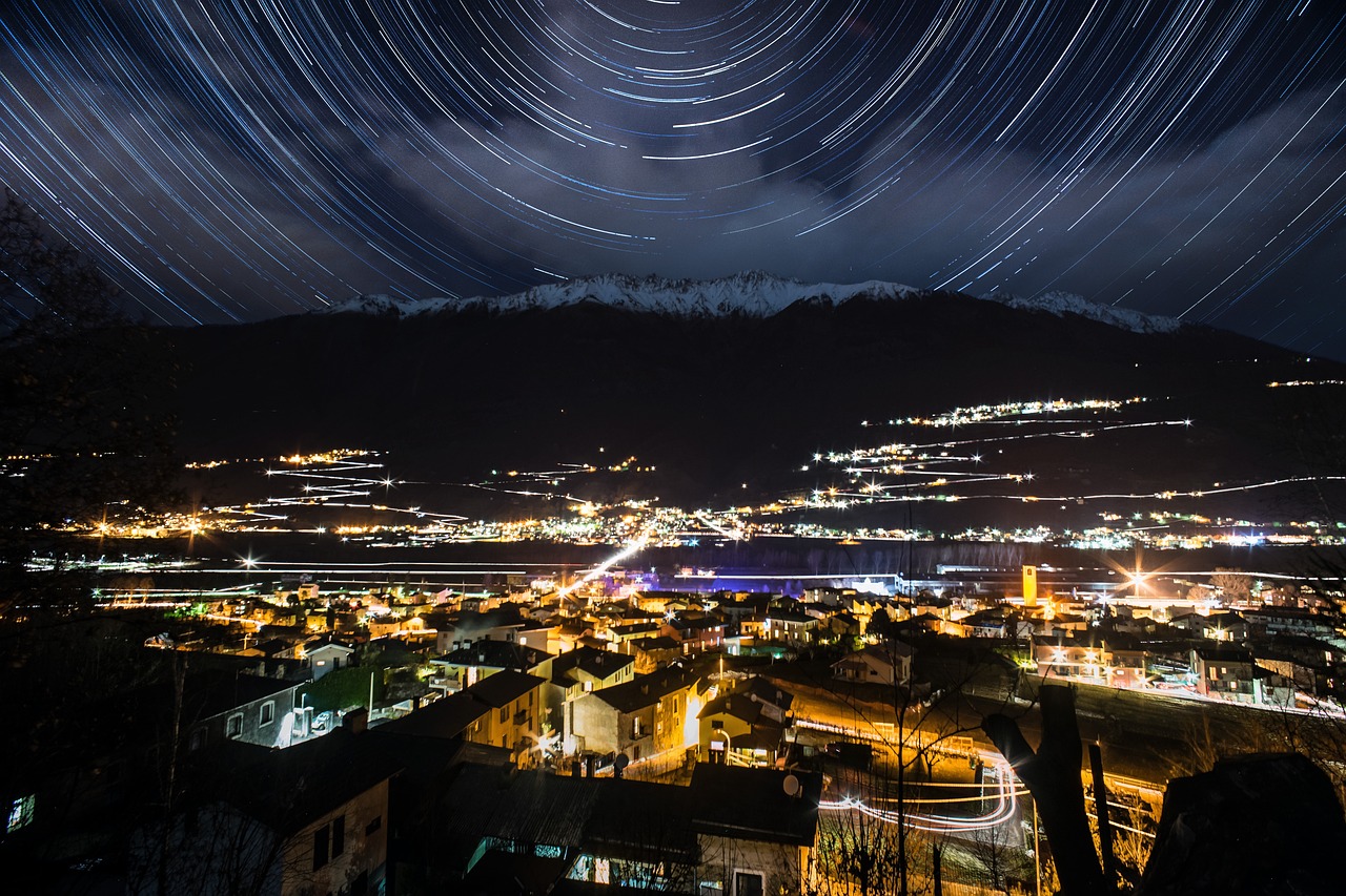 Vista notturna del borgo trentino con cielo stellato e monti sullo sfondo.