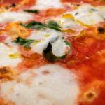 Pizza fritta servita nella tradizionale trattoria napoletana, con vista su un vivace vicolo di Napoli.