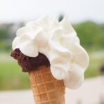 Gelato artigianale in una coppa, con vista su una pittoresca piazza della città famosa per il suo gelato.