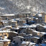 Borgo valdostano immerso nella natura con case tipiche e montagne sullo sfondo.