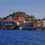 Panorama della città sarda con acque cristalline e spiagge poco affollate.