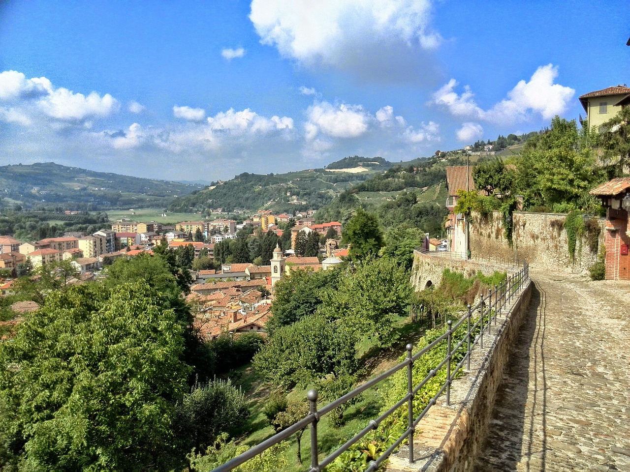 Panorama suggestivo di una località piemontese con case colorate e colline verdi.