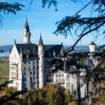 Castello di Neuschwanstein immerso nella nebbia mattutina, con paesaggio incantevole e atmosfera magica.