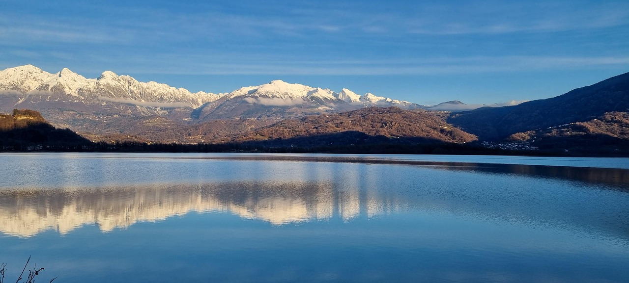 Lago nascosto in Friuli, circondato da montagne e vegetazione lussureggiante.