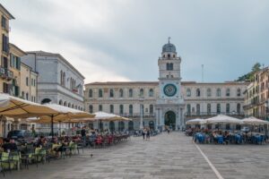Piazza storica affollata a Venezia, circondata da eleganti edifici e monumenti.