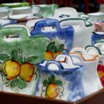 Mercato rionale di Palermo con bancarelle colorate e turisti che esplorano le specialità locali.