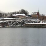 Panoramica invernale di una città costiera con spiagge deserte e il mare calmo sotto un cielo sereno.