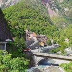 Panorama di un pittoresco paese italiano con stradine acciottolate e case colorate, simile a una cartolina vintage.