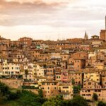 Borgo di Pitigliano al tramonto, con le sue antiche costruzioni in tufo illuminate da una luce dorata.