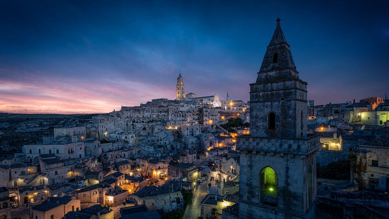 Vista notturna di Matera, case scavate nella roccia illuminate come un presepe.