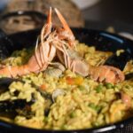 Risotto ai frutti di mare con cozze, gamberi e prezzemolo fresco su un piatto elegante.