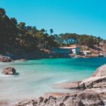 Spiaggia di sabbia dorata con acque turchesi e scogliere a picco sul mare in una località francese.