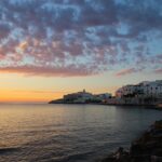 Tramonto mozzafiato sulla spiaggia della Puglia, con colori vivaci che riflettono sul mare.