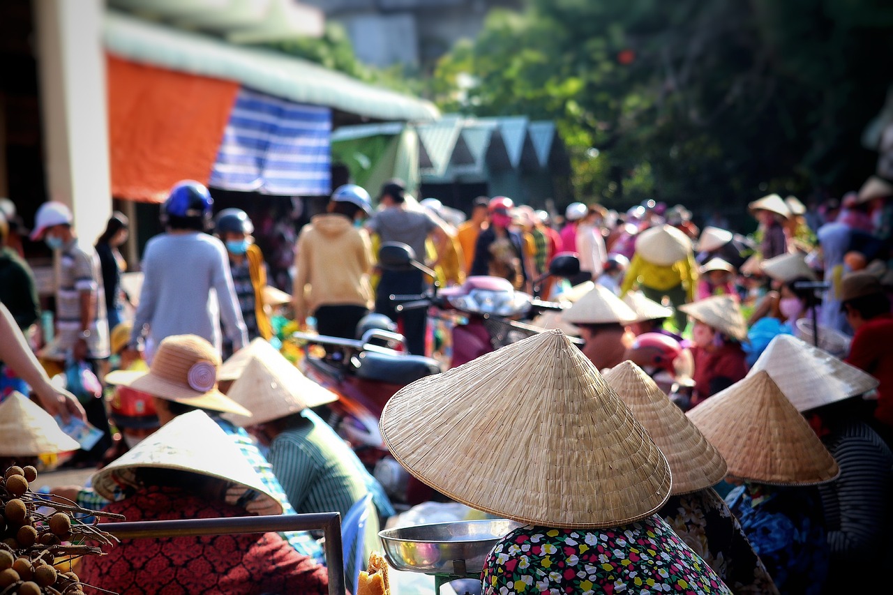 Un venditore ambulante in un mercato turistico affollato, con turisti che osservano le merci.