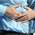 Immagine di una persona che tiene una mano sullo stomaco, simboleggiando il dolore associato al tumore al pancreas.