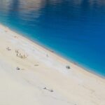 Spiaggia affollata in una delle mete di mare più economiche d'Europa, con ombrelloni e turisti.